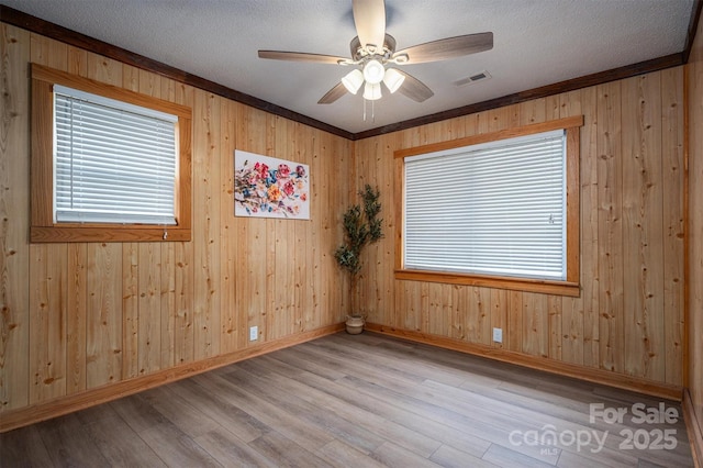 spare room with ceiling fan, a textured ceiling, visible vents, baseboards, and light wood-style floors