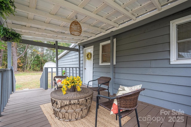 wooden deck featuring an outbuilding, an outdoor fire pit, and a storage unit