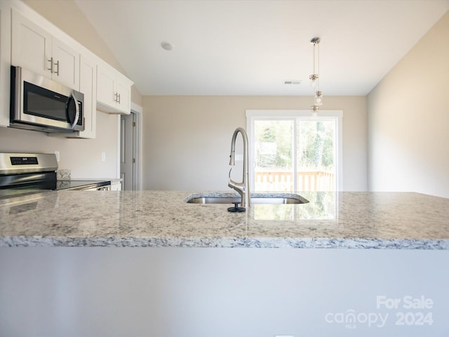 kitchen with light stone countertops, stainless steel appliances, sink, pendant lighting, and white cabinets