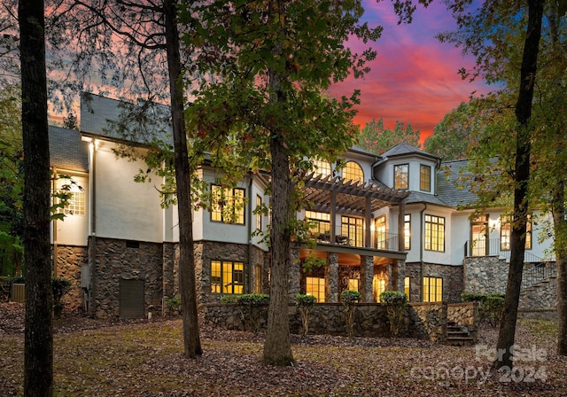 back house at dusk with central AC and a balcony