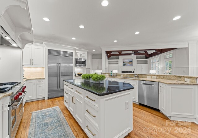 kitchen with built in appliances, light hardwood / wood-style floors, a kitchen island, and white cabinets