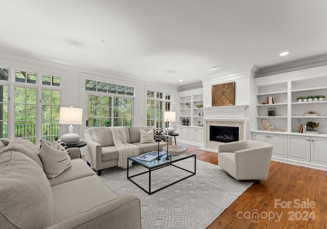 living room featuring ornamental molding, light hardwood / wood-style flooring, and built in features