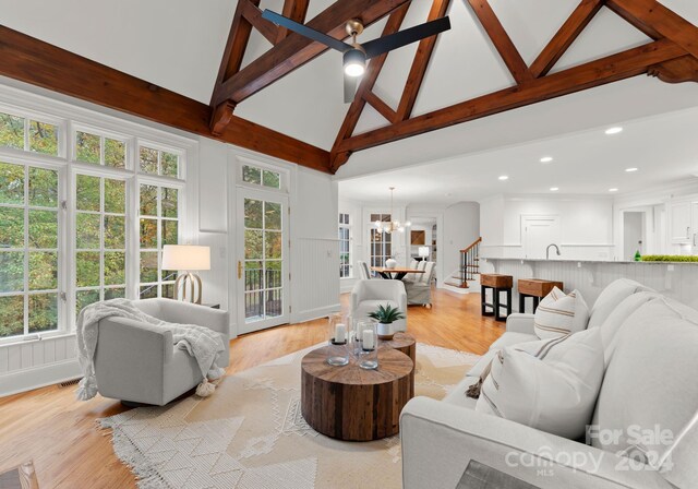 living room with light hardwood / wood-style floors, high vaulted ceiling, and beamed ceiling