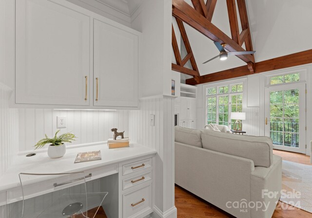 living room with beam ceiling, light hardwood / wood-style flooring, and high vaulted ceiling