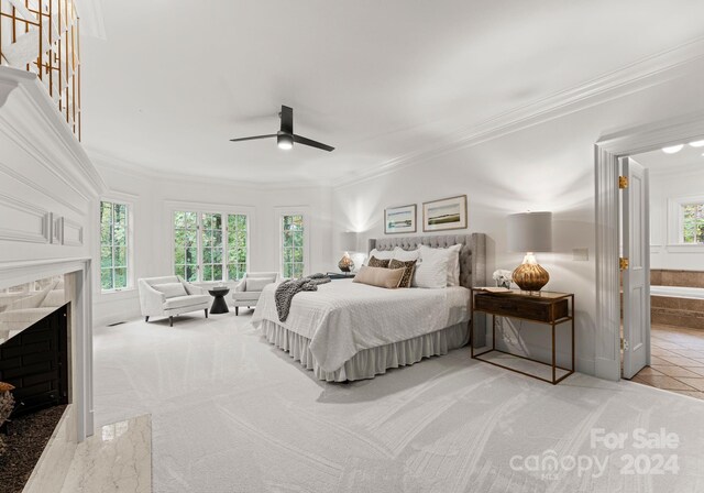 carpeted bedroom featuring ceiling fan, ornamental molding, multiple windows, and a fireplace