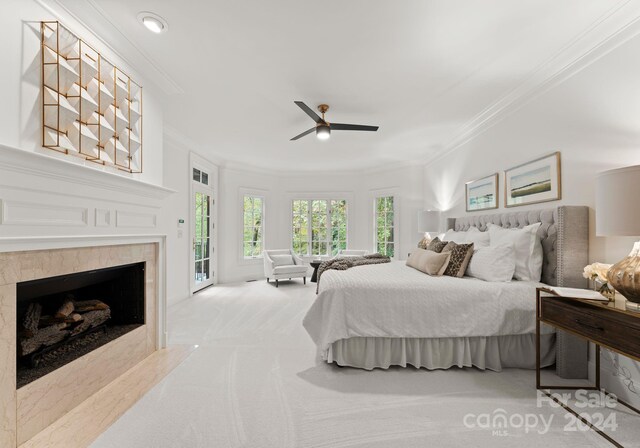 carpeted bedroom with crown molding, access to exterior, a tile fireplace, and ceiling fan