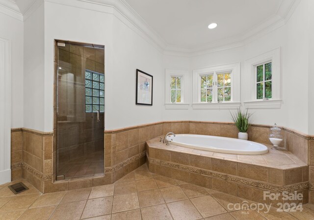 bathroom with ornamental molding and shower with separate bathtub