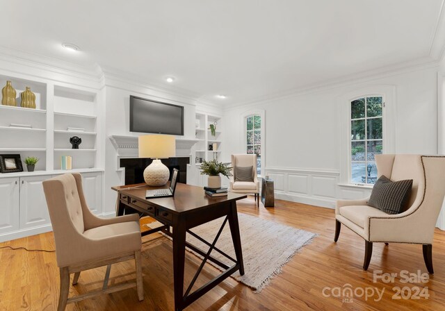 office space featuring ornamental molding, built in shelves, and light hardwood / wood-style floors