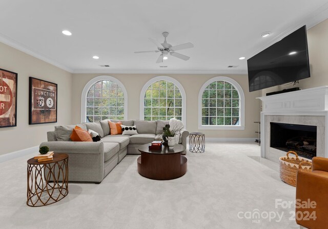 carpeted living room featuring a premium fireplace, crown molding, and ceiling fan