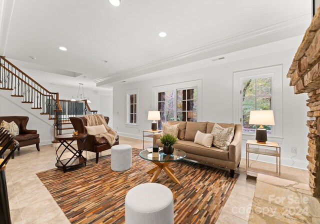 tiled living room featuring ornamental molding and a chandelier