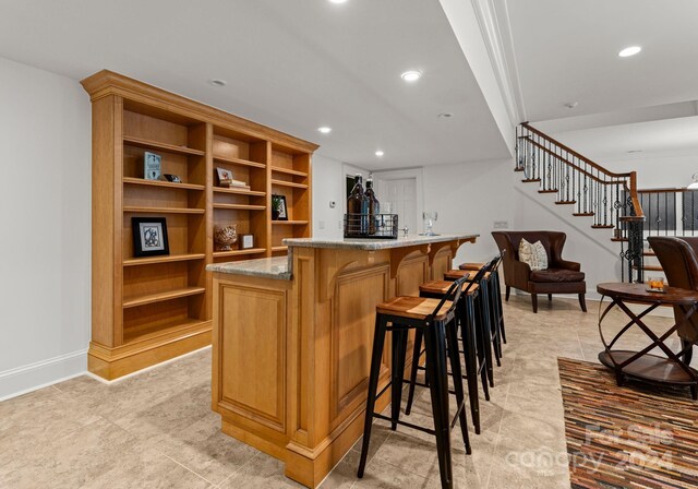 bar featuring ornamental molding and light stone countertops