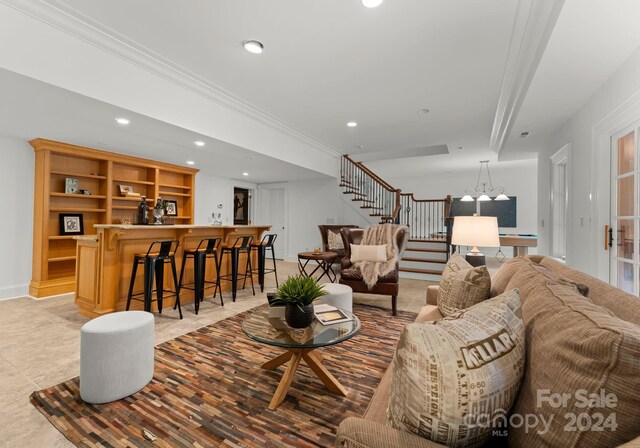 living room featuring light tile patterned flooring, crown molding, bar area, and a chandelier