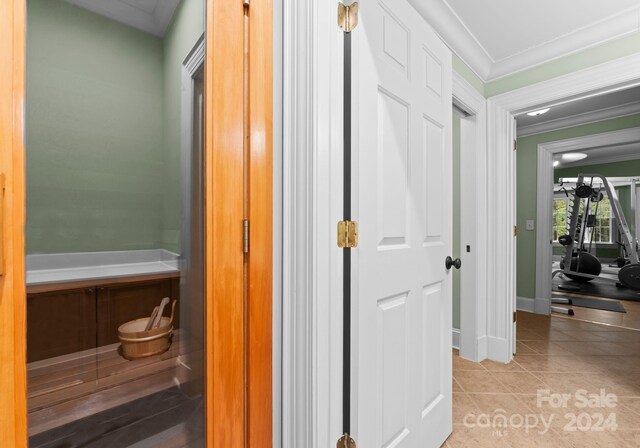 hallway featuring ornamental molding and light tile patterned floors