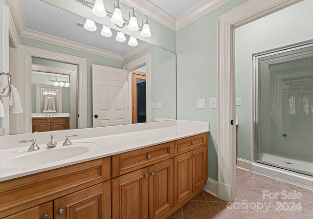 bathroom with vanity, crown molding, tile patterned floors, and a shower with door