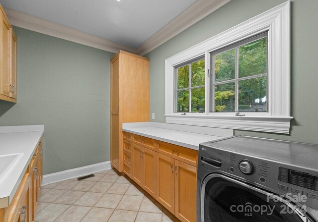 laundry room with washer / dryer, crown molding, cabinets, and light tile patterned floors