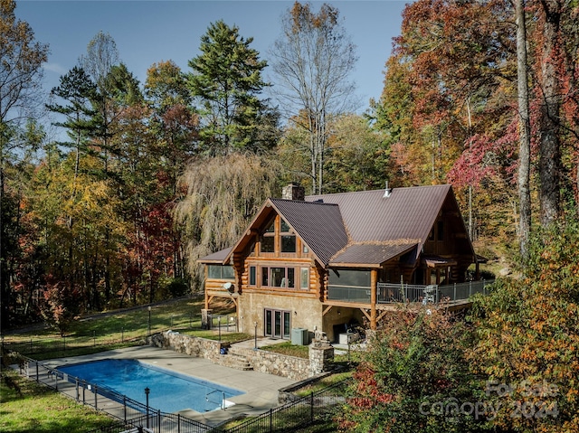 rear view of property with central air condition unit, a patio, a covered pool, and a balcony