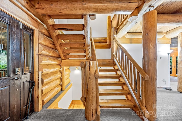 stairway featuring beam ceiling, rustic walls, and a wealth of natural light