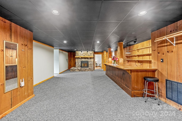 bar featuring wood walls, carpet, and a fireplace