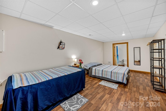 bedroom with dark hardwood / wood-style floors and a paneled ceiling