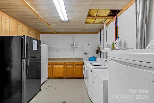 clothes washing area with cabinets, independent washer and dryer, and wooden walls