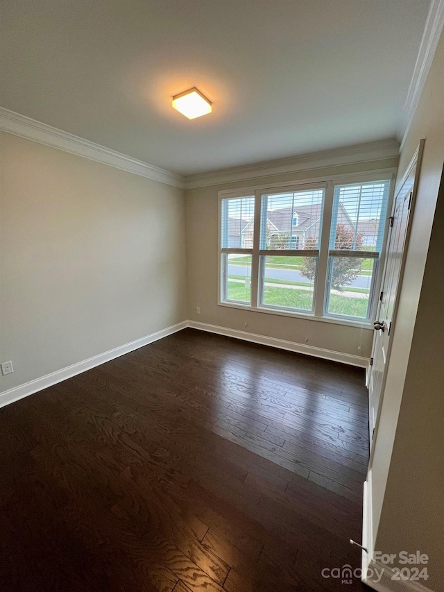 unfurnished room with ornamental molding and dark wood-type flooring