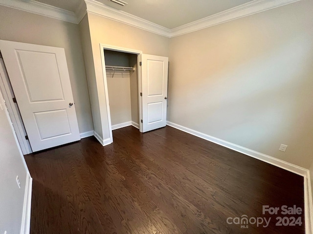 unfurnished bedroom with a closet, ornamental molding, and dark hardwood / wood-style floors