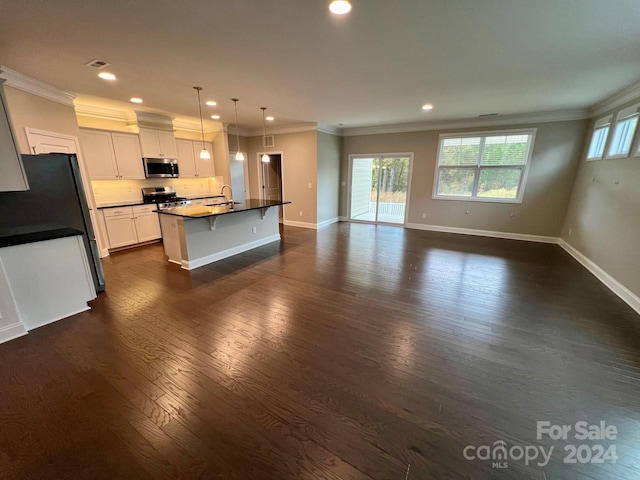 kitchen featuring appliances with stainless steel finishes, an island with sink, hanging light fixtures, white cabinets, and dark hardwood / wood-style floors