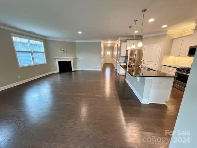 kitchen with a kitchen island with sink, hanging light fixtures, stainless steel appliances, sink, and white cabinetry