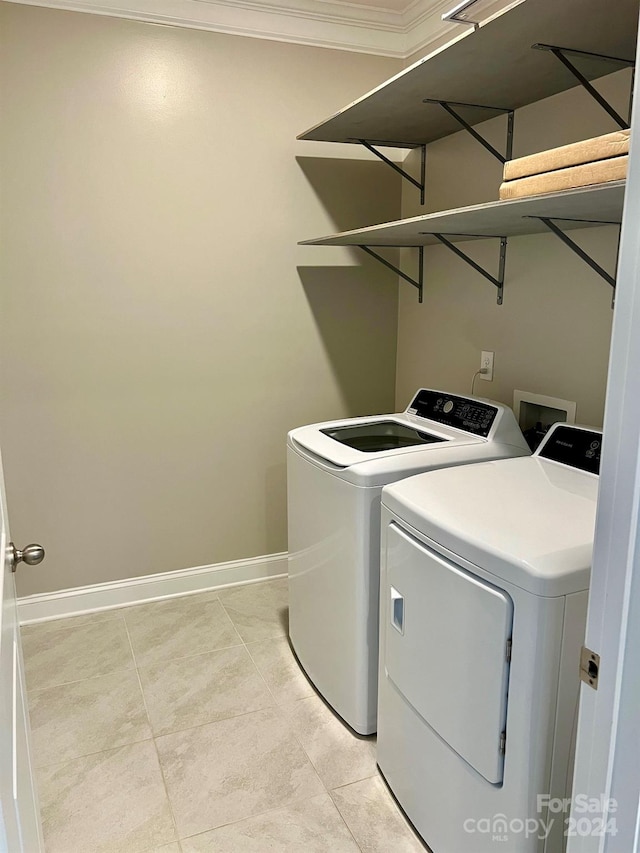 clothes washing area with ornamental molding, light tile patterned flooring, and washer and dryer