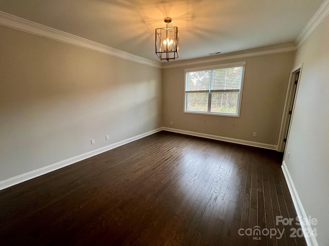 spare room with ornamental molding, an inviting chandelier, and dark hardwood / wood-style floors