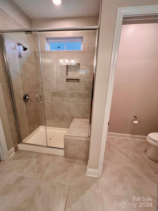 bathroom featuring toilet, walk in shower, and tile patterned flooring