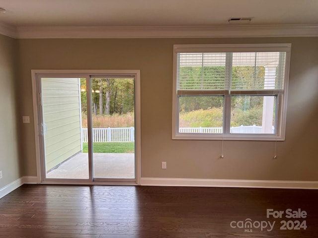 empty room featuring ornamental molding and dark hardwood / wood-style flooring