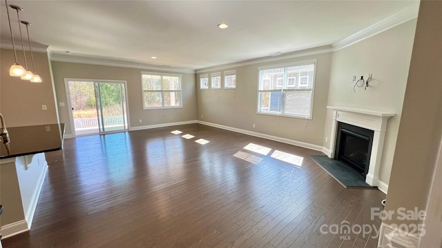 unfurnished living room with baseboards, a glass covered fireplace, ornamental molding, dark wood-style flooring, and recessed lighting