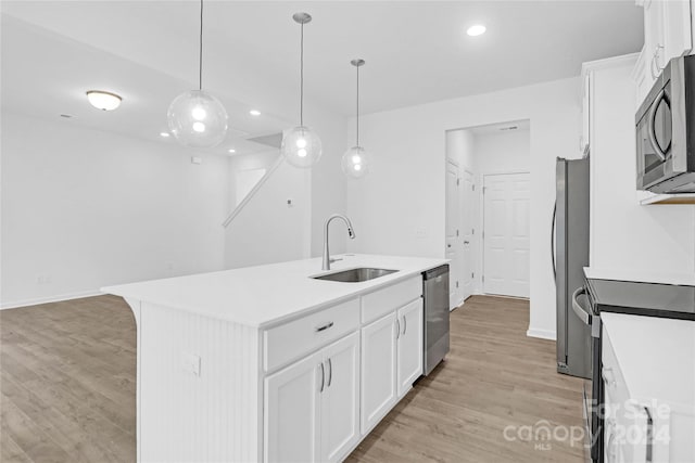 kitchen featuring appliances with stainless steel finishes, sink, white cabinetry, and an island with sink