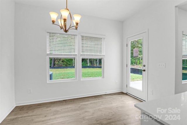 unfurnished dining area featuring light wood-type flooring and an inviting chandelier