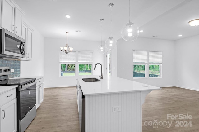 kitchen with stainless steel appliances, a kitchen island with sink, sink, decorative light fixtures, and white cabinets