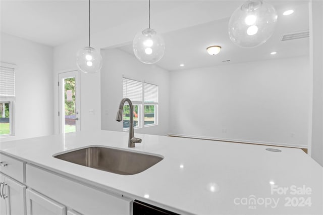 kitchen with white cabinetry, sink, a healthy amount of sunlight, and decorative light fixtures