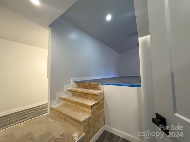 stairway featuring wood-type flooring and lofted ceiling