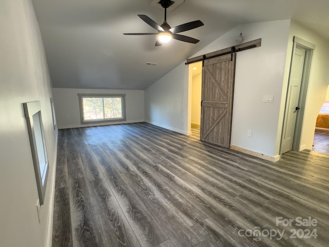 additional living space with ceiling fan, lofted ceiling, a barn door, and dark hardwood / wood-style flooring