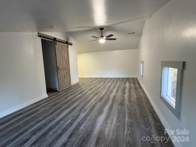 unfurnished living room featuring lofted ceiling, a barn door, ceiling fan, and dark hardwood / wood-style flooring