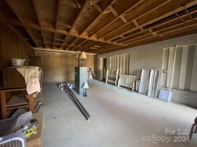 miscellaneous room featuring brick wall and concrete flooring