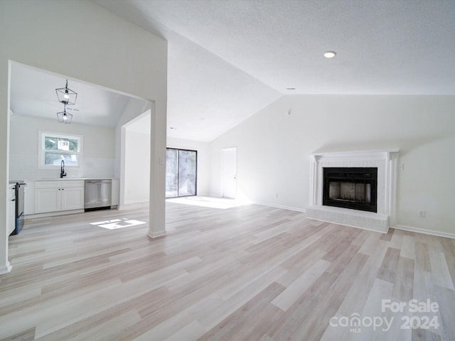 unfurnished living room with lofted ceiling, sink, and light hardwood / wood-style flooring