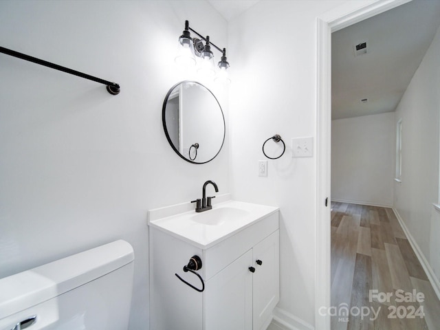 bathroom with vanity, toilet, and hardwood / wood-style flooring