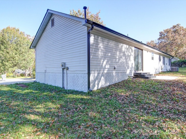 view of side of property featuring central AC unit and a lawn