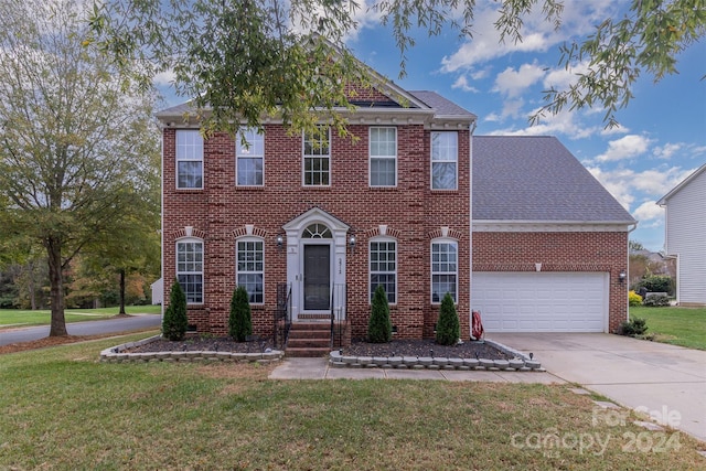 colonial home featuring a garage and a front lawn