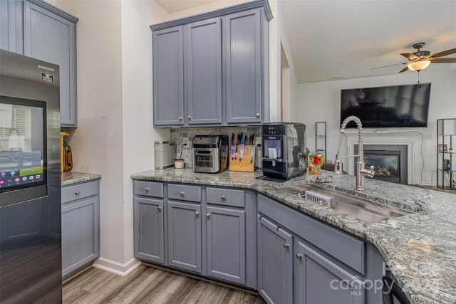 kitchen featuring hardwood / wood-style floors, black fridge, sink, and gray cabinetry