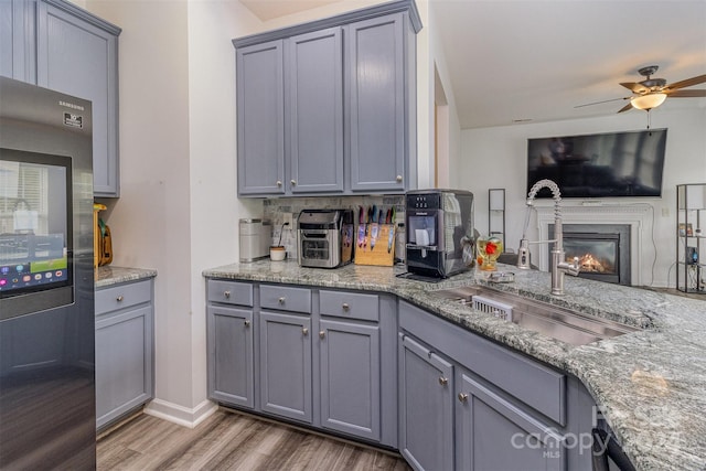 kitchen featuring wood-type flooring, fridge, sink, and gray cabinetry