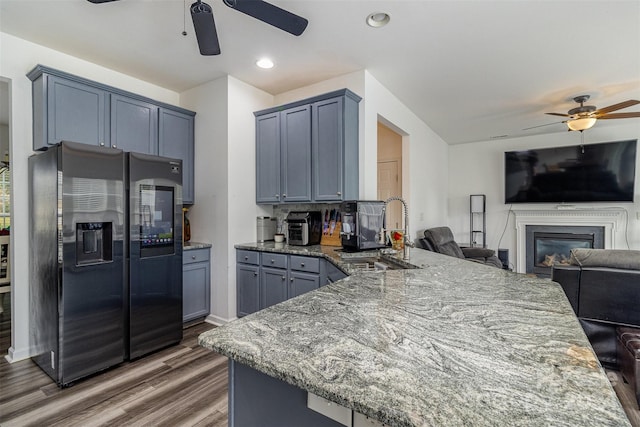 kitchen featuring black fridge, dark wood-type flooring, sink, and light stone countertops