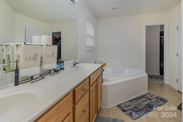 bathroom with tile patterned flooring, vanity, and tiled tub