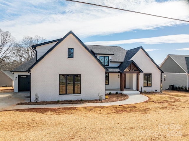 modern inspired farmhouse featuring a garage, driveway, brick siding, and central AC